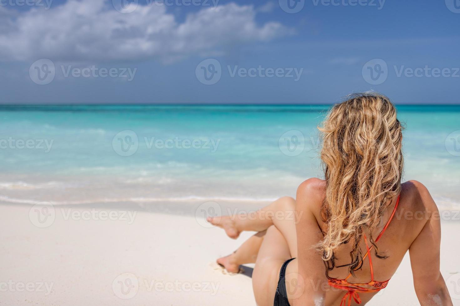 junge modefrau, lange haare, sexy beine entspannen sich am strand. glücklicher Insellebensstil. weißer Sand, blauer bewölkter Himmel und kristallklares Meer des tropischen Strandes. Urlaubsparadies. ozeanstrandlandschaft, luxusreisen foto