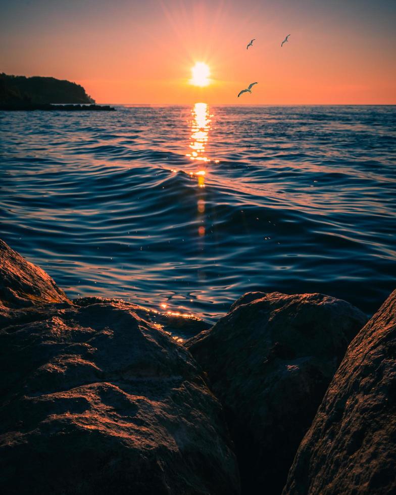 braune Felsformationen in der Nähe eines Gewässers während des Sonnenuntergangs foto