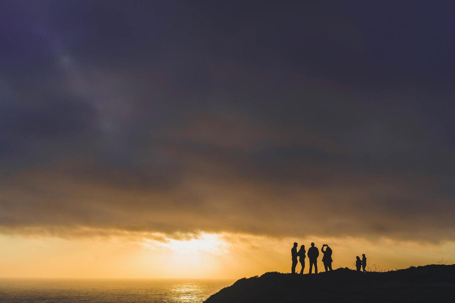 Silhouette Menschen auf Klippen zur goldenen Stunde foto