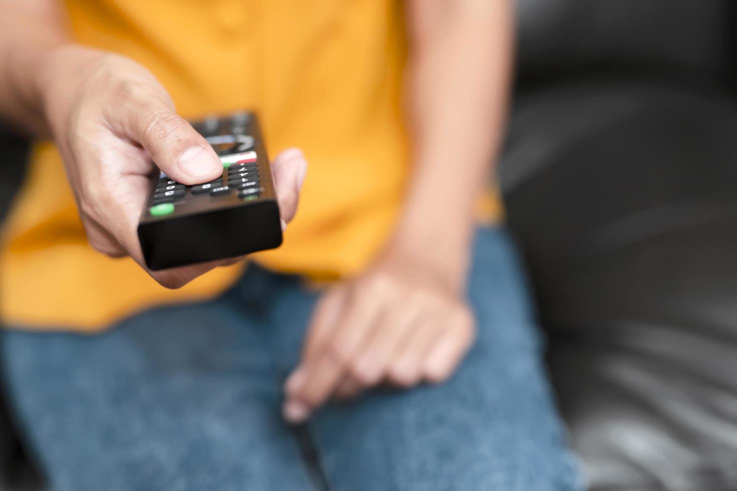 Frau drückt Tasten auf der TV-Fernbedienung foto