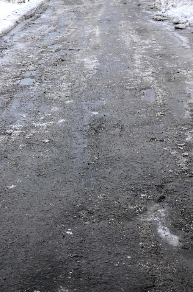 Beschädigte Asphaltstraße mit Schlaglöchern, die durch Frost- und Tauzyklen im Winter verursacht wurden. schlechte Straße foto