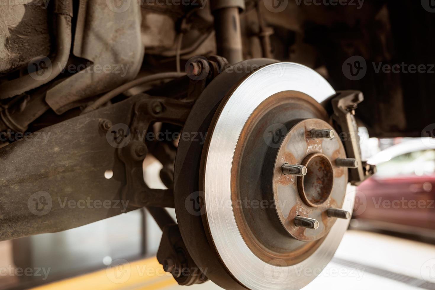 auto scheibenbremssystem. autoaufhängung im prozess des neuen reifenwechsels in der garage. auto scheibenbremse mechaniker prüfen und reparieren. Bremsscheibenrotor. auto im reifenwechselprozess an der servicestation. foto