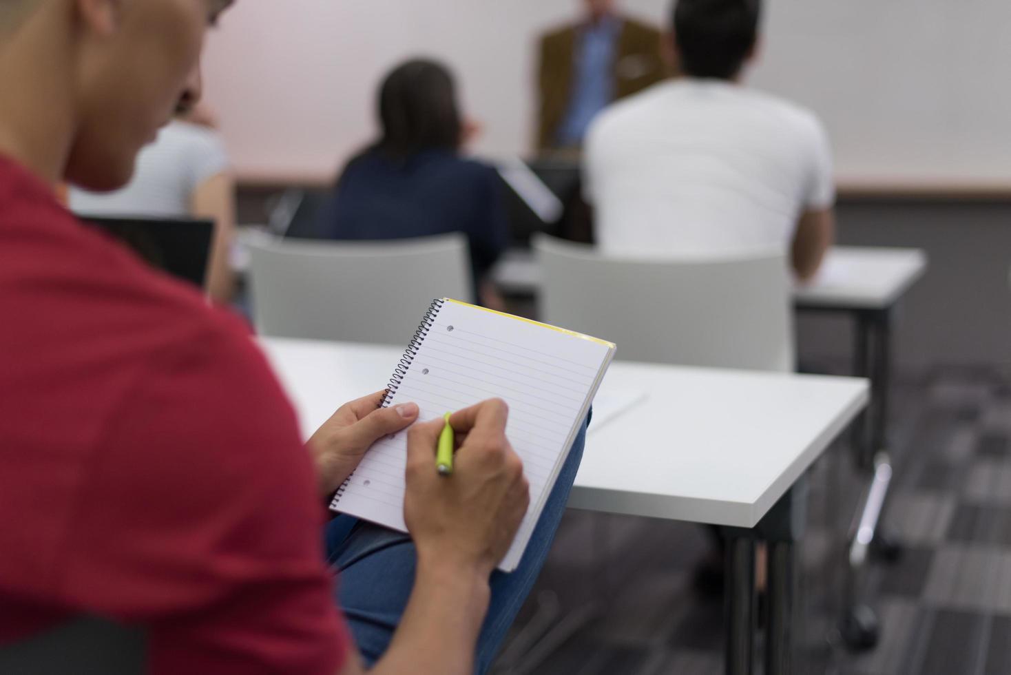 männlicher schüler, der sich im klassenzimmer notizen macht foto