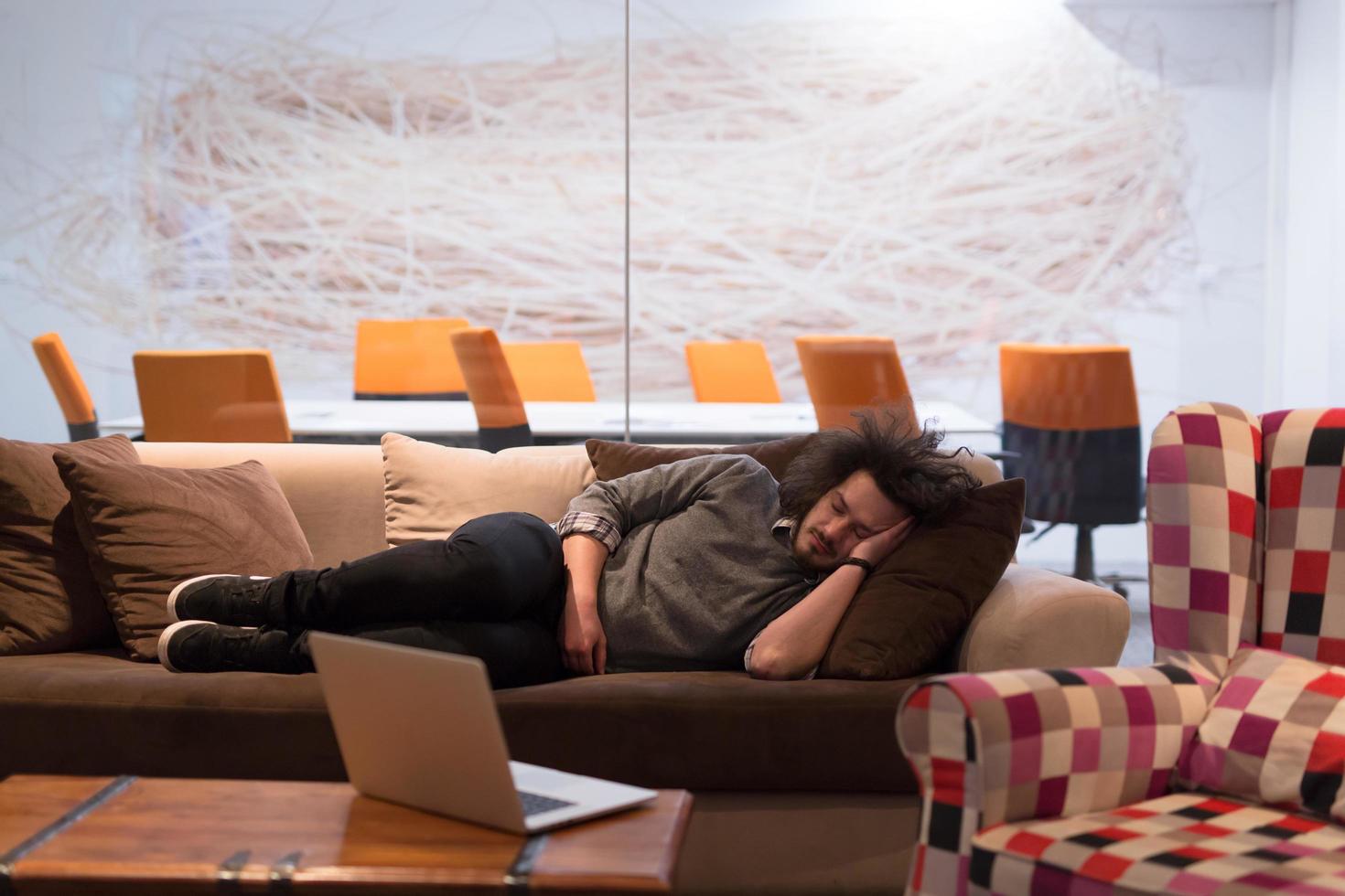 Mann schläft auf einem Sofa in einem Kreativbüro foto