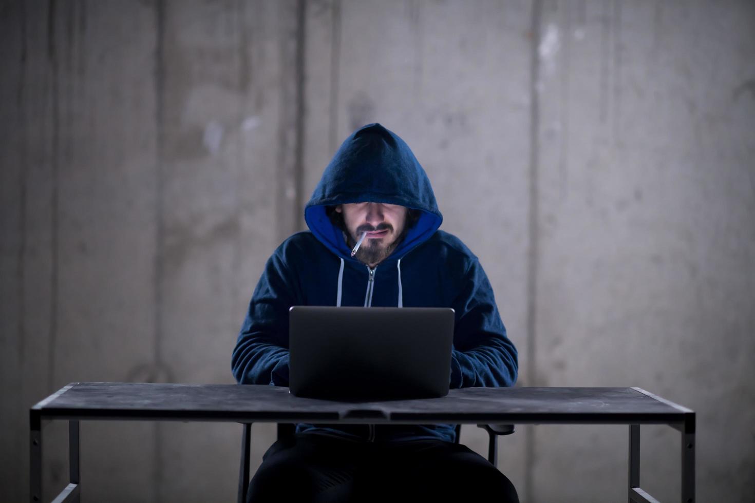 junger hacker, der laptop-computer verwendet, während er im dunklen büro arbeitet foto