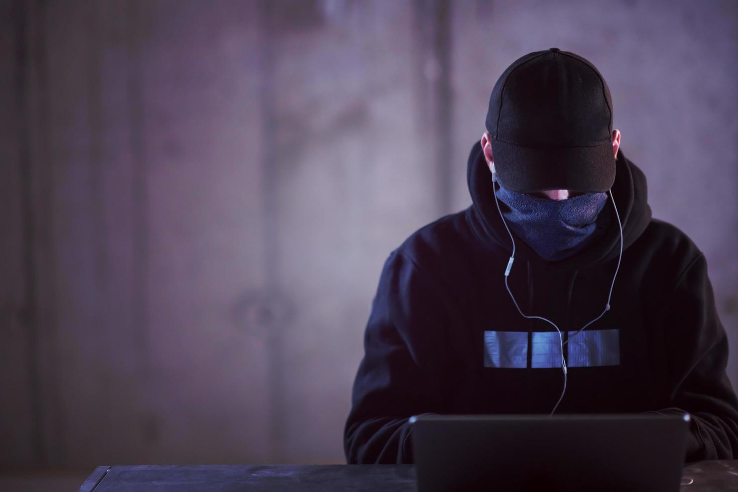 talentierter hacker, der einen laptop verwendet, während er im dunklen büro arbeitet foto