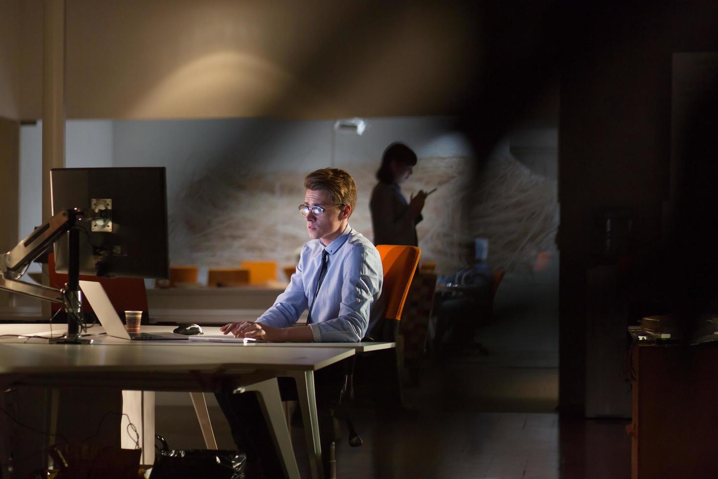 Mann, der im dunklen Büro am Computer arbeitet foto