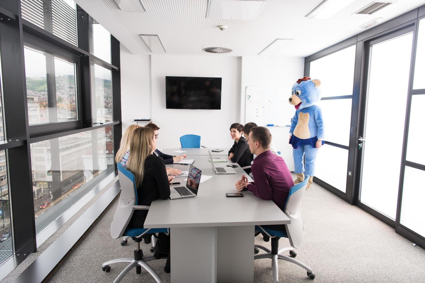 als bär verkleideter chef hat spaß mit geschäftsleuten im trendigen büro foto