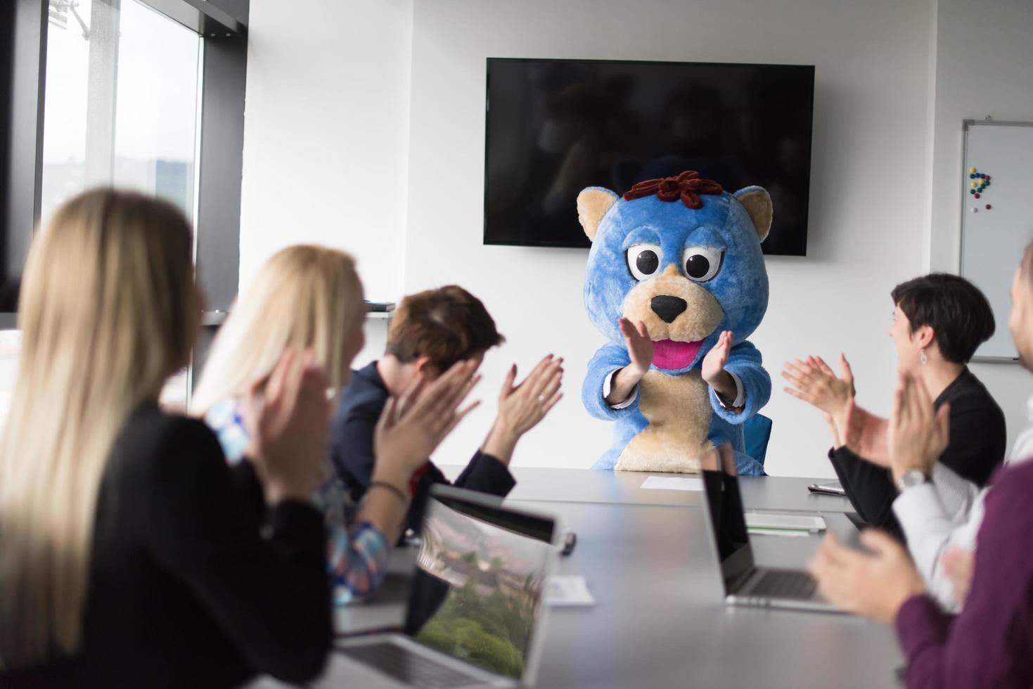 als bär verkleideter chef hat spaß mit geschäftsleuten im trendigen büro foto