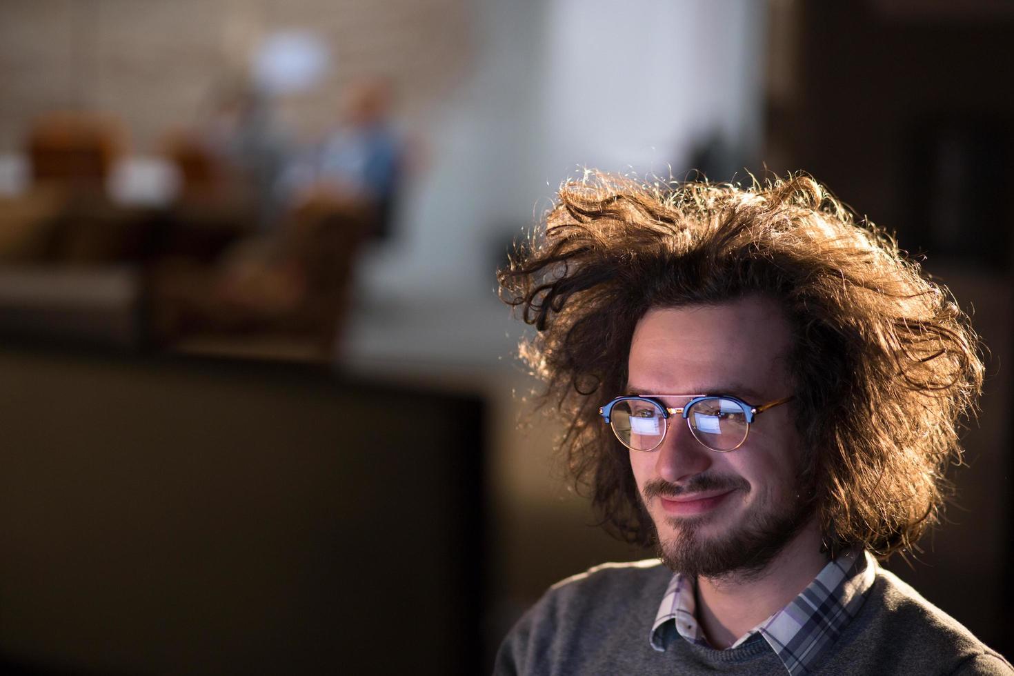 Mann, der im dunklen Büro am Computer arbeitet foto