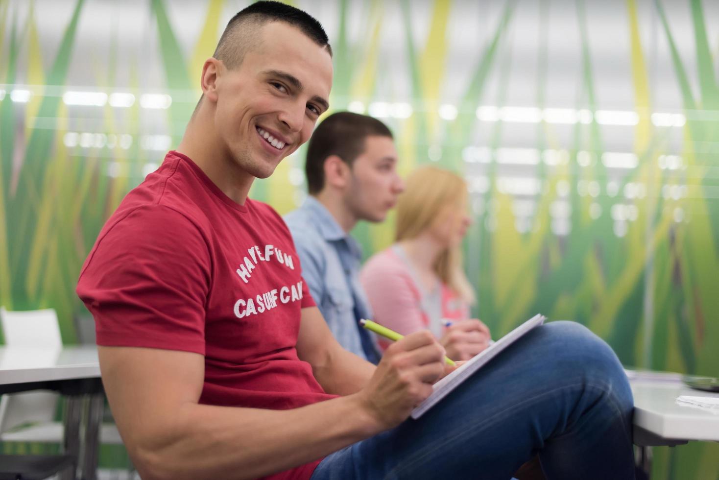 männlicher schüler, der sich im klassenzimmer notizen macht foto