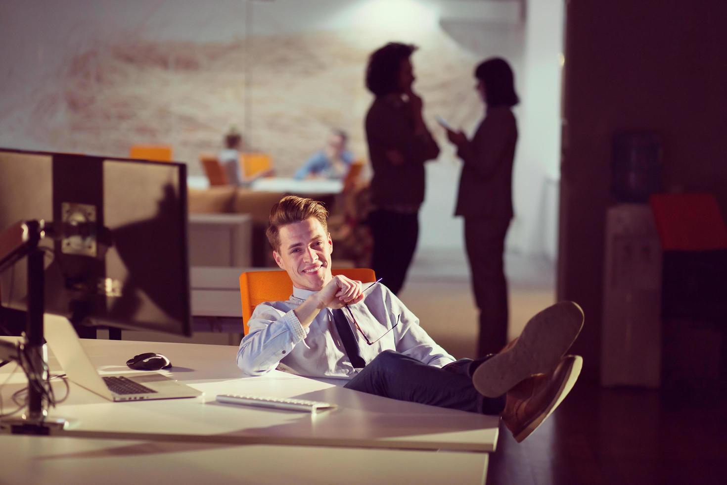 Geschäftsmann sitzt mit Beinen auf dem Schreibtisch im Büro foto