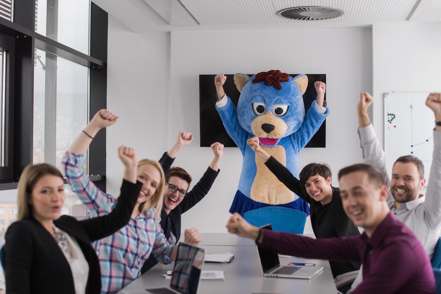 als bär verkleideter chef hat spaß mit geschäftsleuten im trendigen büro foto