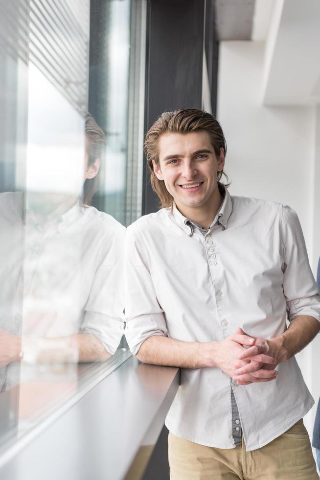 Junger Geschäftsmann im Startup-Büro am Fenster foto