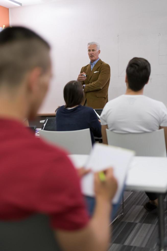 männlicher schüler, der sich im klassenzimmer notizen macht foto