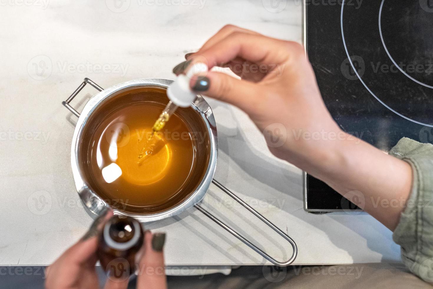 Draufsicht auf heiße Kakaobutter, die in einem Wasserbad zur Herstellung von Körperpflegekosmetik geschmolzen wird. der Kochprozess, die Zugabe von aromatischen Ölen. Spa zu Hause. Kleinunternehmen foto