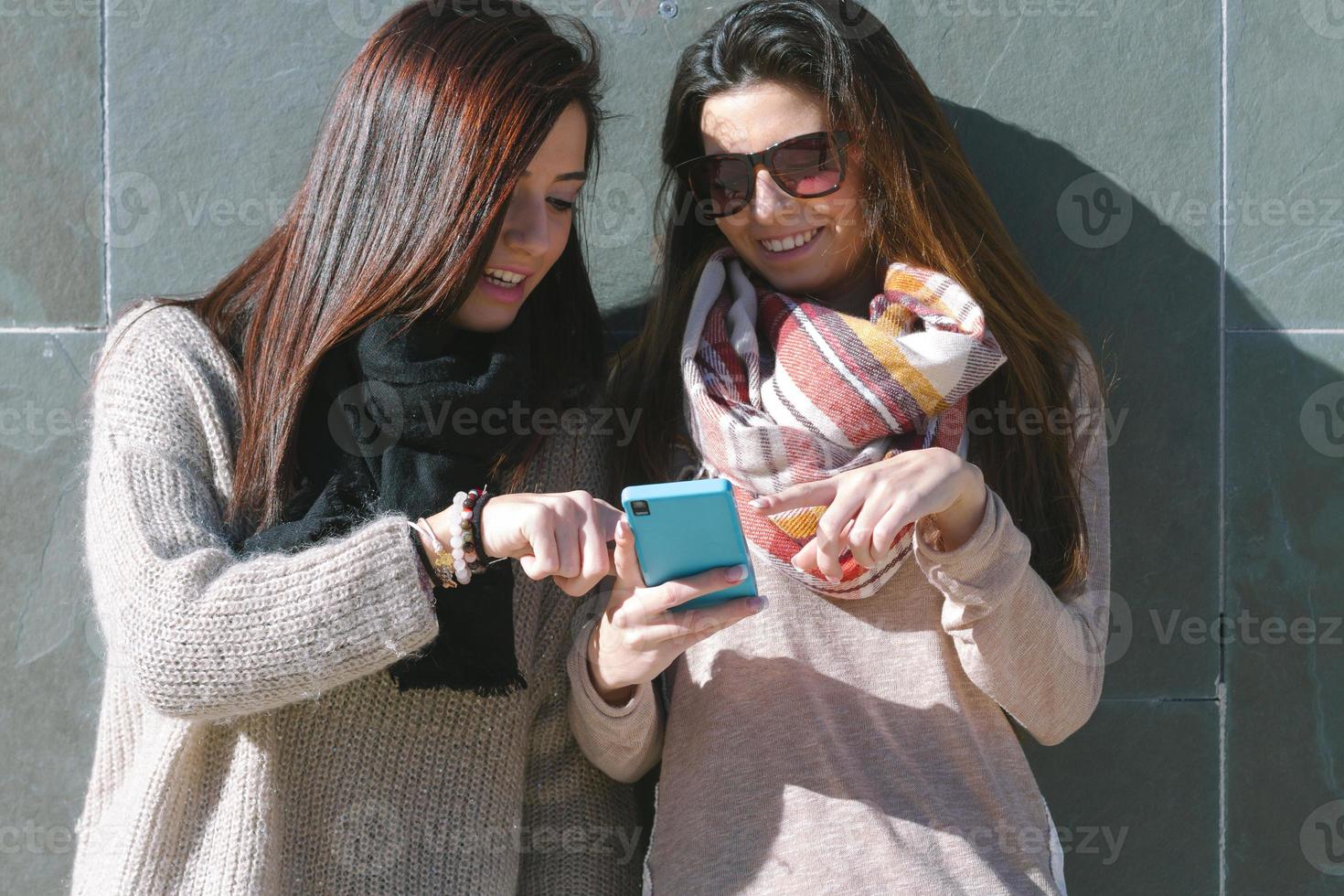 junge Mädchen & Freunde, die mit einem Smartphone stehen foto