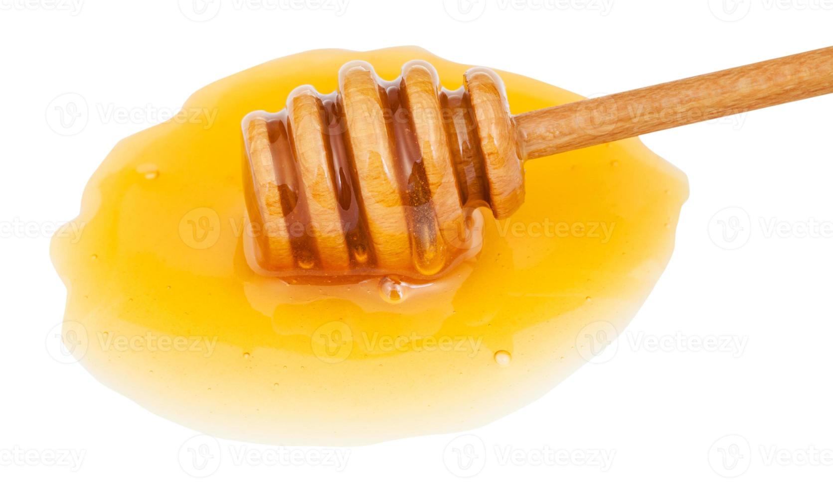 Pfütze aus klarem Honig und Holzstab aus nächster Nähe foto