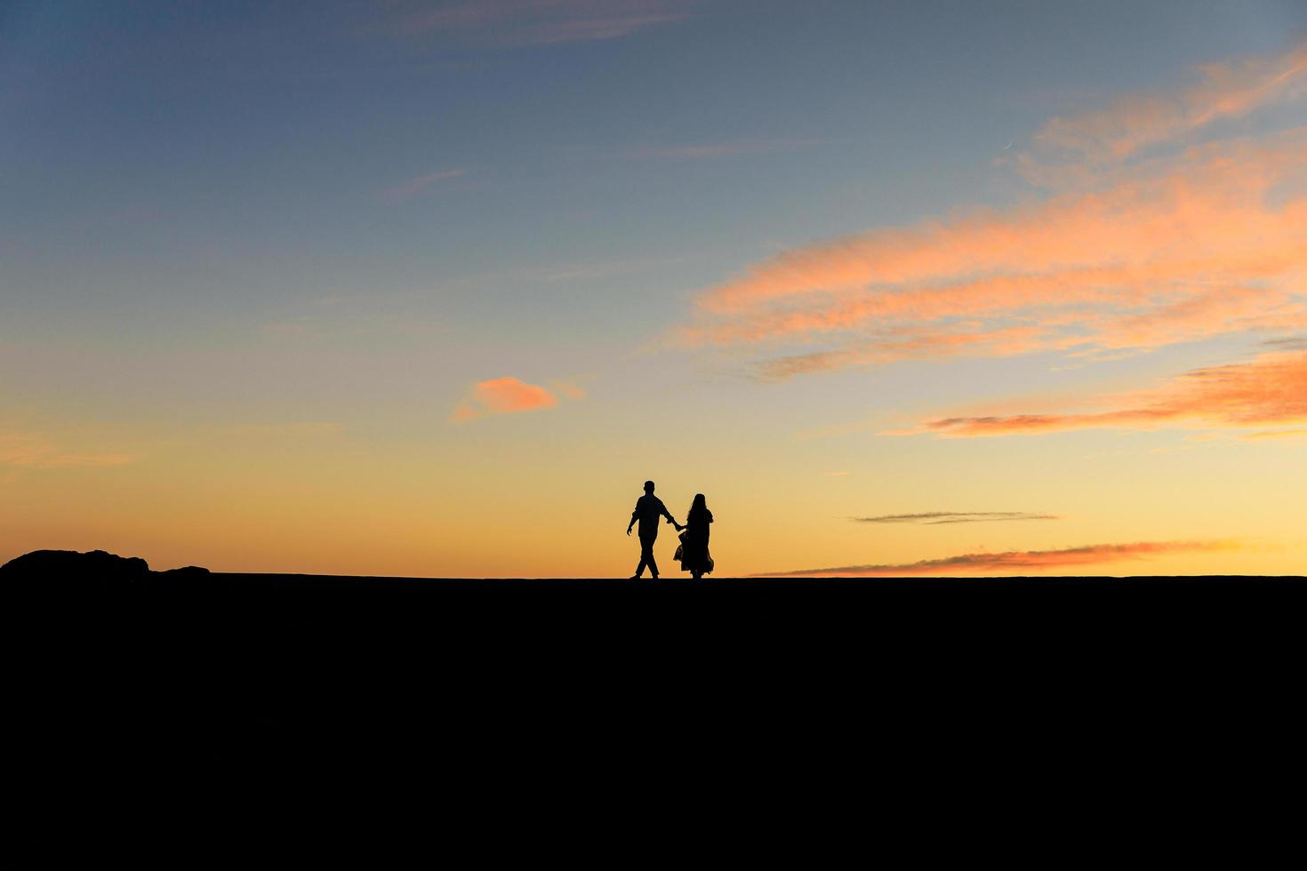 Silhouetten von zwei Personen bei Sonnenuntergang foto