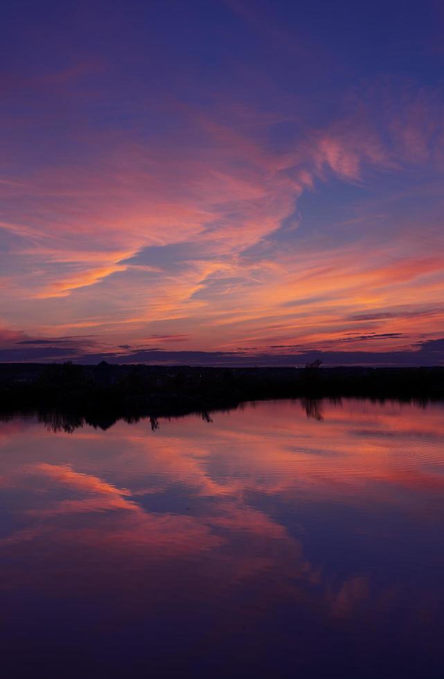 orangefarbene Wolken reflektieren klares blaues Wasser foto