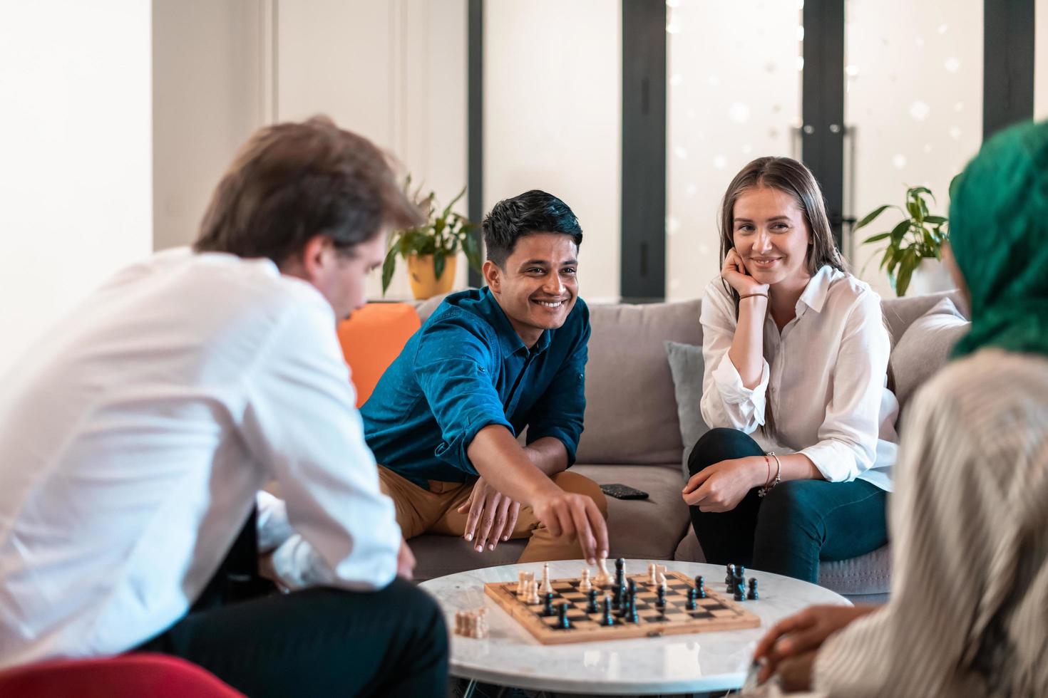 multiethnische gruppe von geschäftsleuten, die schach spielen, während sie eine pause im entspannungsbereich eines modernen startbüros machen. selektiver Fokus foto