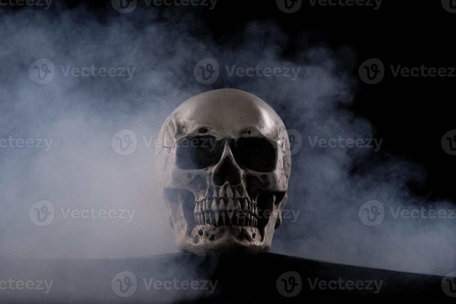 Halloween menschlicher Schädel auf einem alten Holztisch auf schwarzem Hintergrund. Form des Schädelknochens für Totenkopf auf dem Halloween-Festival, das Horror, böse Zahnangst und beängstigend zeigt, Kopierraum foto