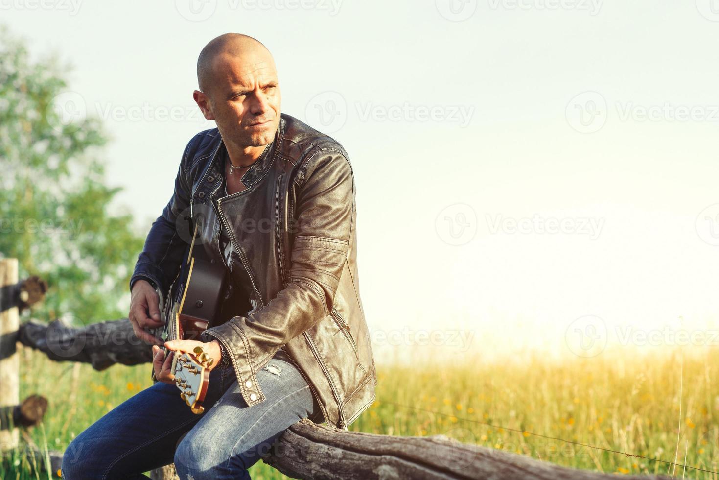 Sänger mit Gitarre auf einem Zaun auf der Wiese foto