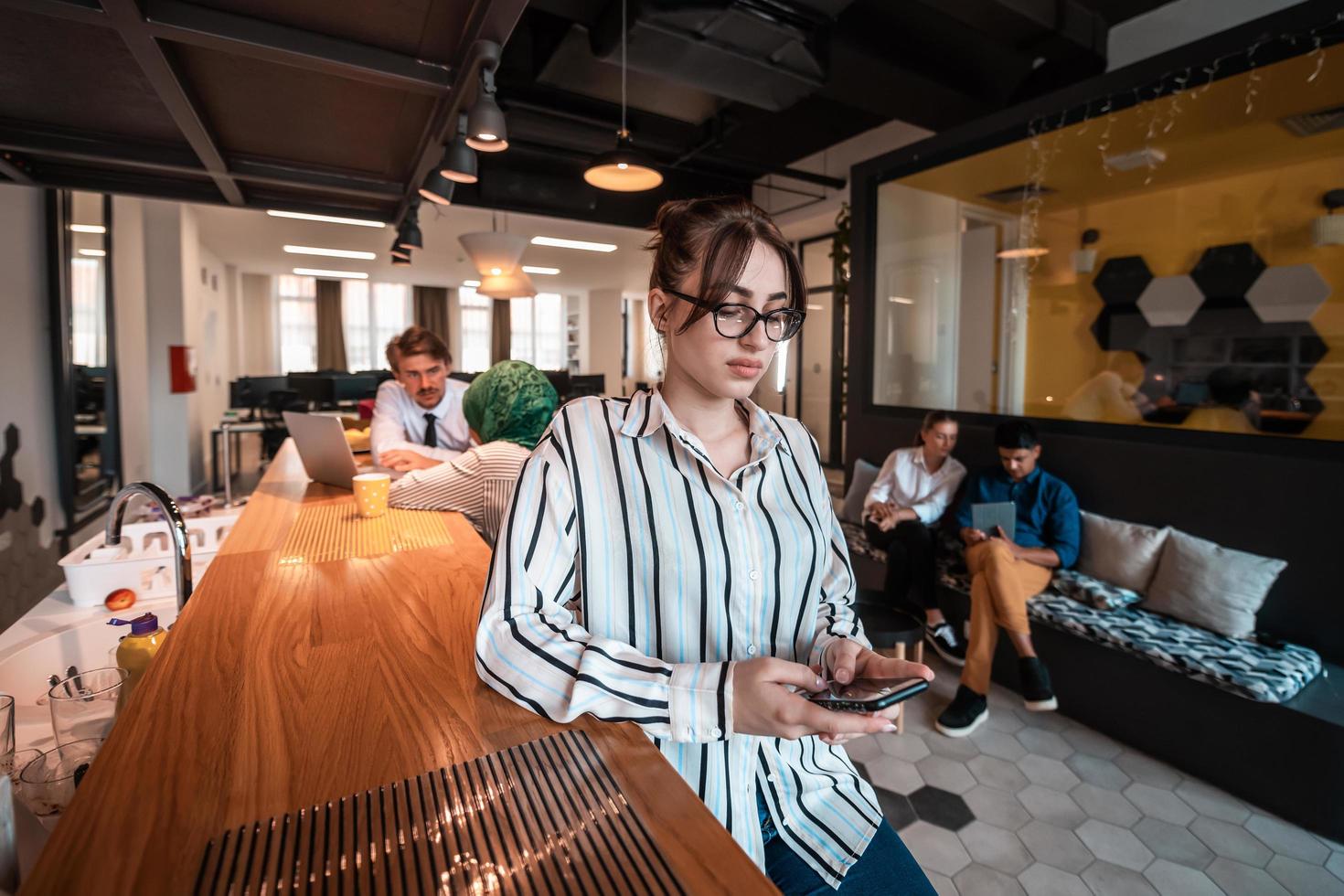 Geschäftsfrau mit Brille mit Handy im modernen Startup-Großraumbüro. selektiver Fokus foto