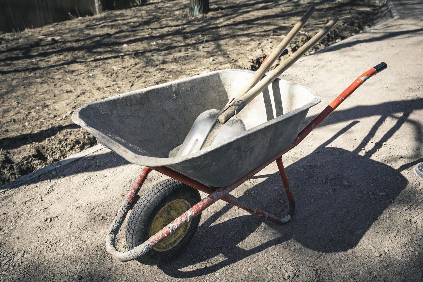 Alte, zuverlässig funktionierende Schubkarre mit Schaufeln auf einer Baustelle foto