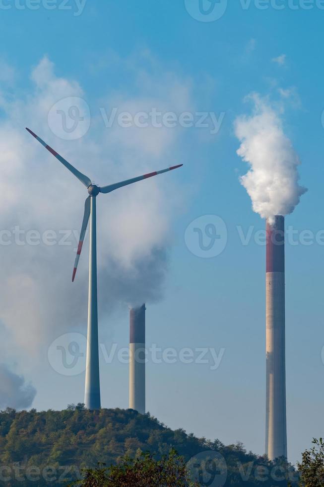 Windmühle mit rauchenden Schornsteinen vor blauem Himmel foto