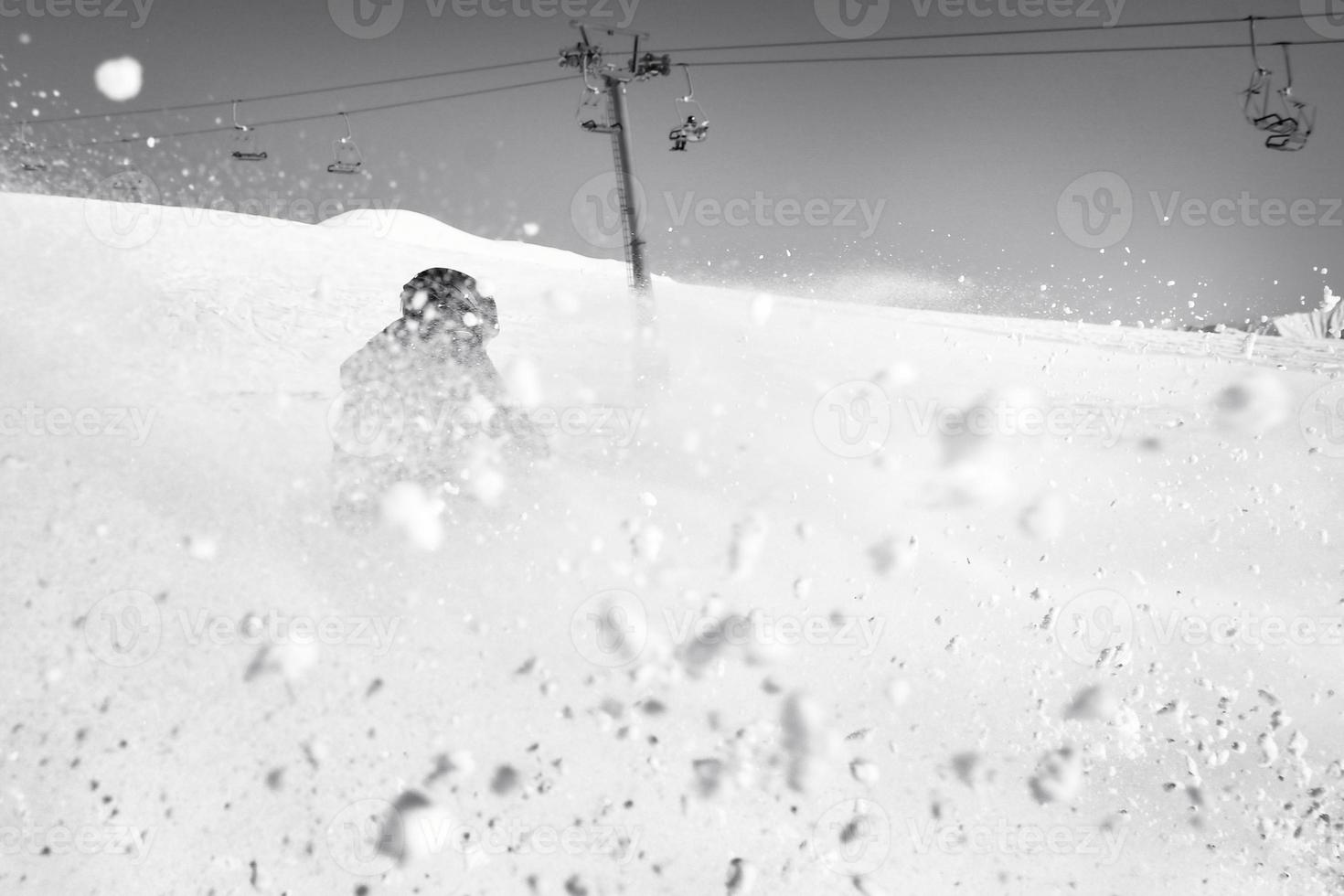 dynamisches bild eines skifahrers auf der piste in den alpen. Skifahrerin im weichen Schnee. aktiver winterurlaub, skifahren an sonnigen tagen. skifahrten auf der strecke mit wirbeln von frischem schnee foto