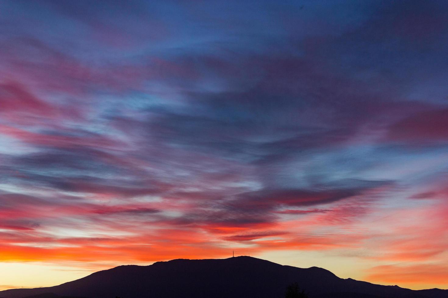 bunte Sonnenuntergangswolken über Berg foto