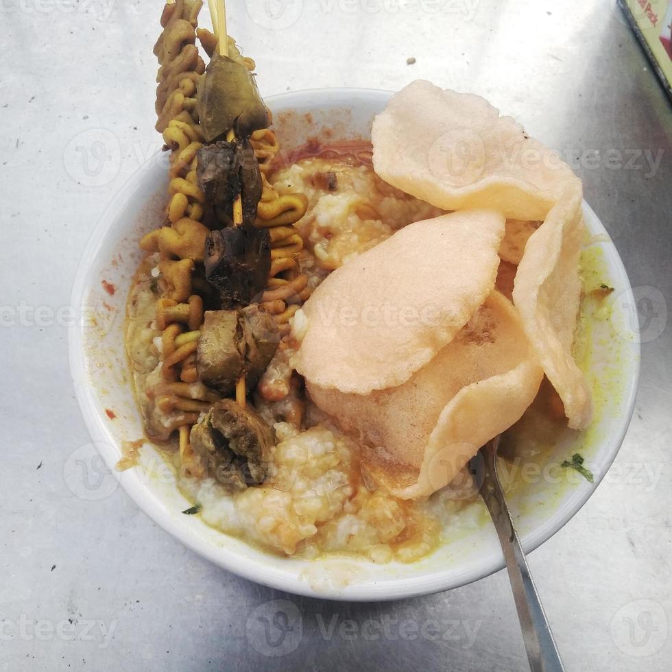 Hühnerbrei ist das beliebteste Frühstück der Indonesier, das mit Reiscrackern serviert wird foto