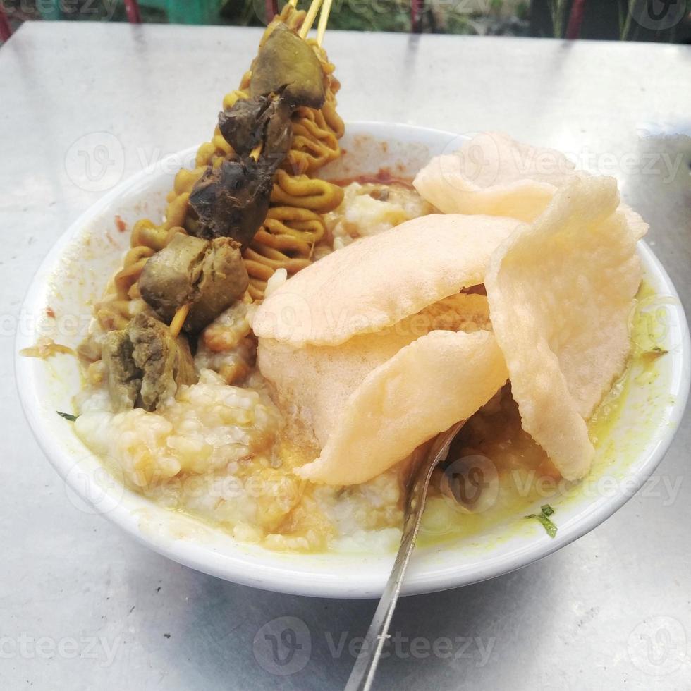 Hühnerbrei ist das beliebteste Frühstück der Indonesier, das mit Reiscrackern serviert wird foto