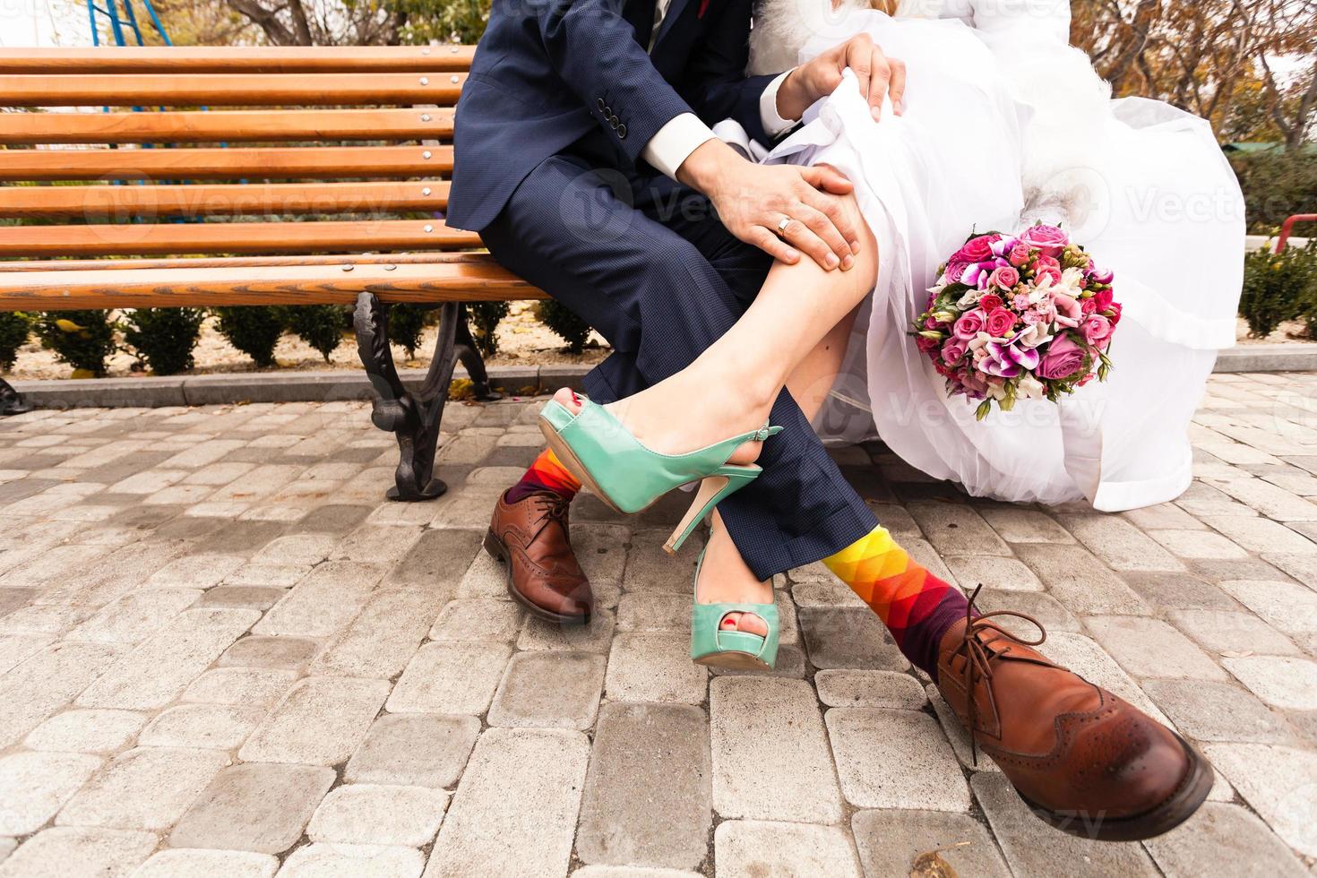 Braut und Bräutigam in hellen Kleidern auf der Bank foto