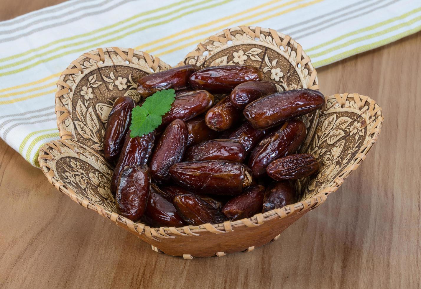 datteln obst in einem korb auf hölzernem hintergrund foto