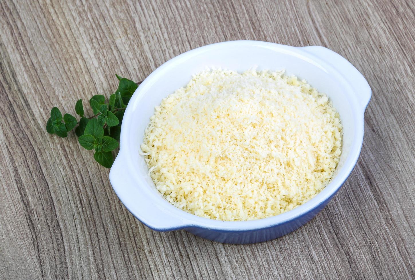 zerkleinerter Parmesan in einer Schüssel auf Holzhintergrund foto