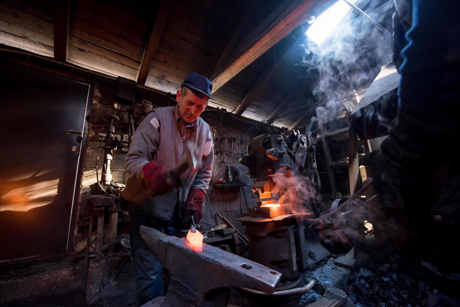 Schmied, der das geschmolzene Metall manuell schmiedet foto