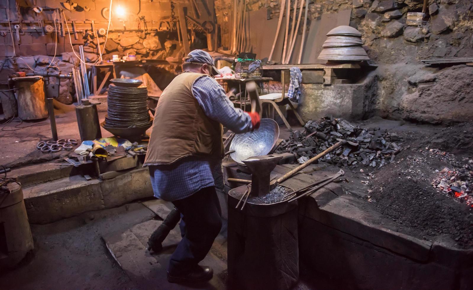 traditioneller Schmied, der das geschmolzene Metall manuell schmiedet foto