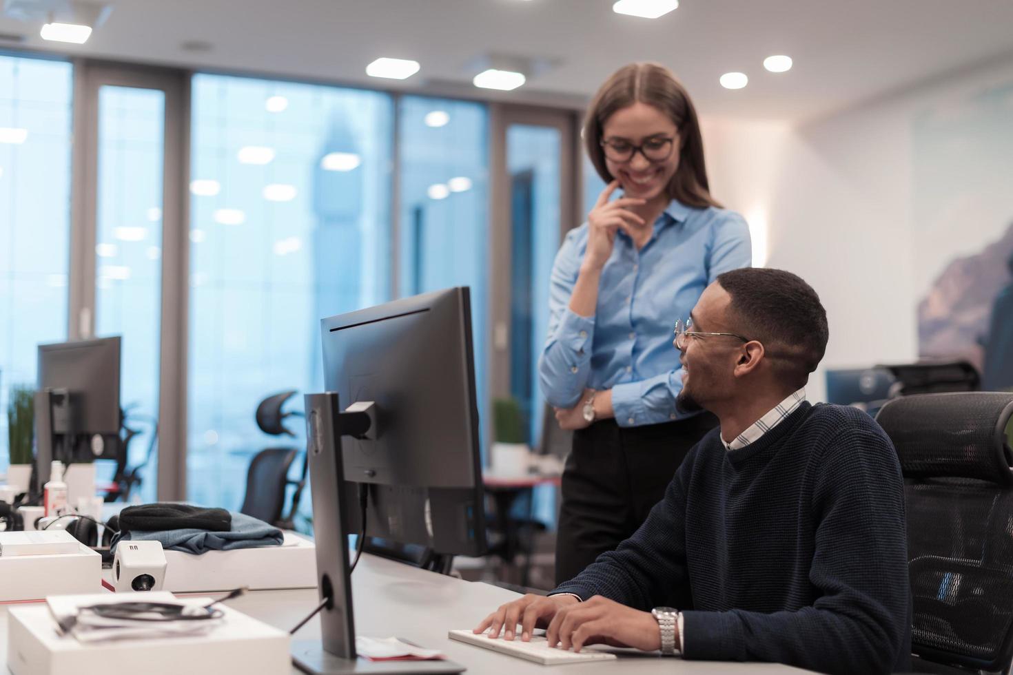 junge lächelnde frau, die einer ernsthaften afroamerikanischen mitarbeiterprojektstrategie erklärt. diverse startkollegen studenten frau und mann reden über die arbeit in modernen büros mit computer. foto