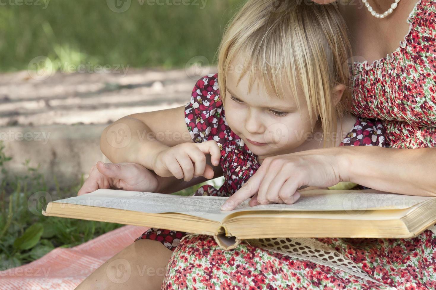 Mädchen sieht etwas in Büchern mit Mutter foto