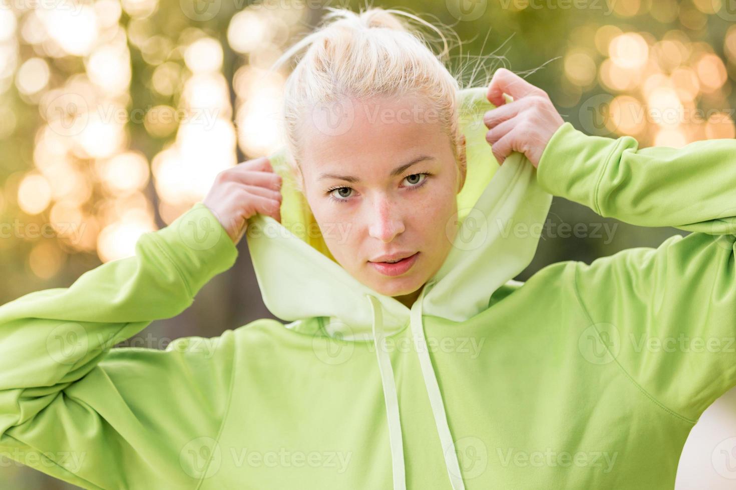 selbstbewusste sportliche Frau, die modischen grünen Kapuzenpulli trägt. foto