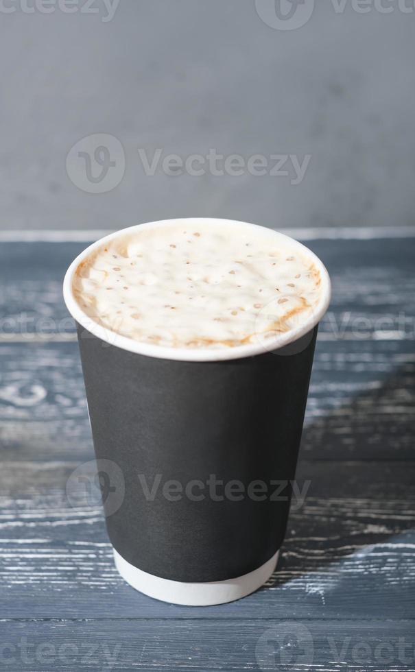 Kaffee zum Mitnehmen im Pappbecher. Kaffee mit Milchschaum, Latte oder Cappuccino auf Holztisch. Getränke zum Mitnehmen in plastikfreien Bechern. foto