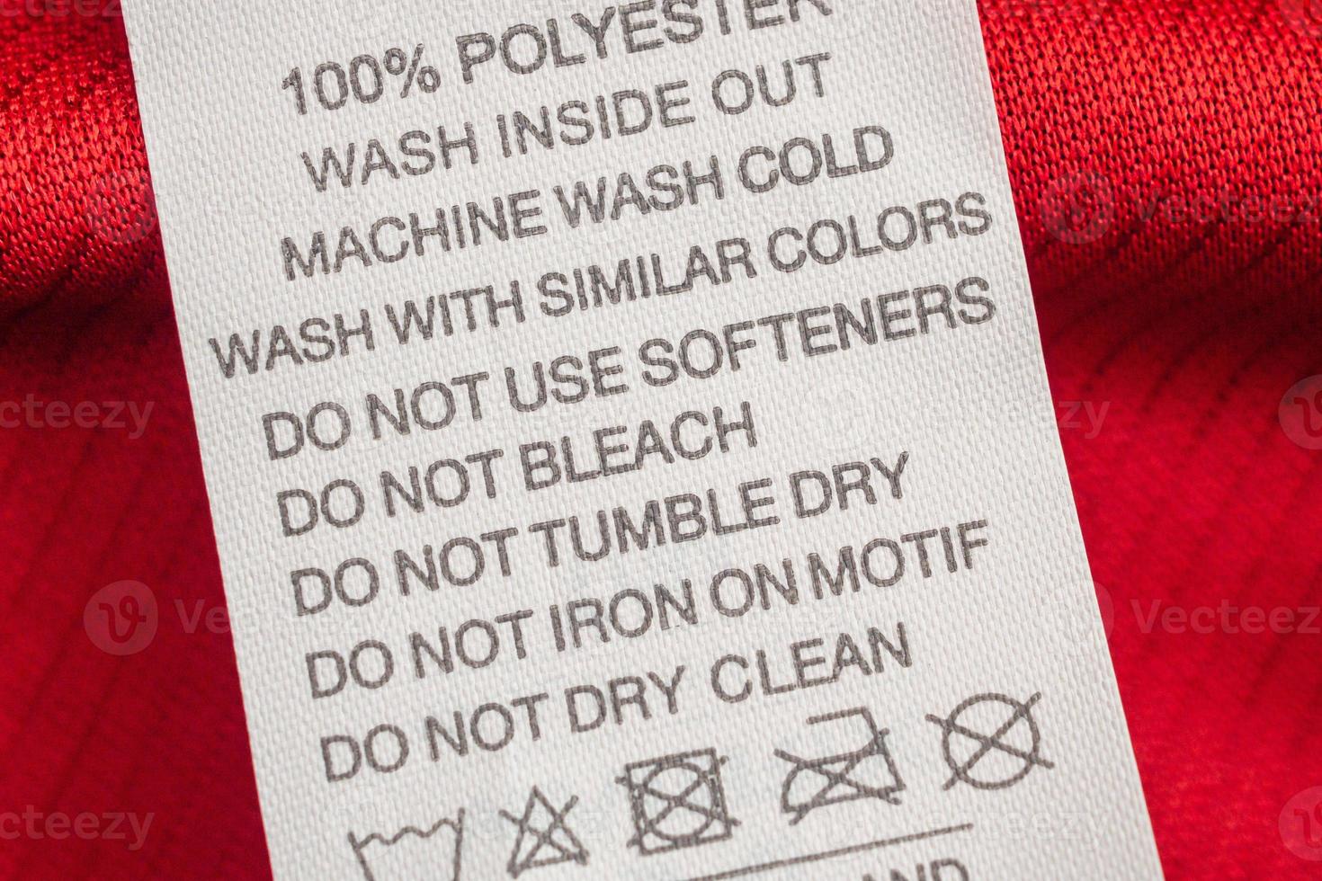 weiße Wäschepflege Waschanleitung Kleideretikett auf rotem Jersey-Polyester-Sporthemd foto