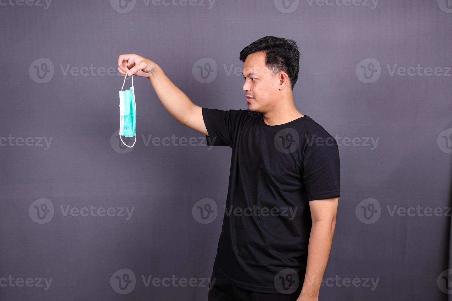 asiatischer mann, der einen mundschutz oder eine maske trägt, um zu verhindern, dass er bei der arbeit krank wird. isoliert auf grauem Hintergrund foto