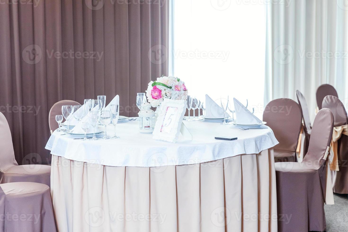 ausgefallener tisch zum abendessen mit blumenkomposition im restaurant, luxuriöser innenhintergrund. Hochzeit elegante Bankettdekoration und Artikel für Speisen, die vom Catering-Service auf dem weißen Tisch arrangiert werden. foto