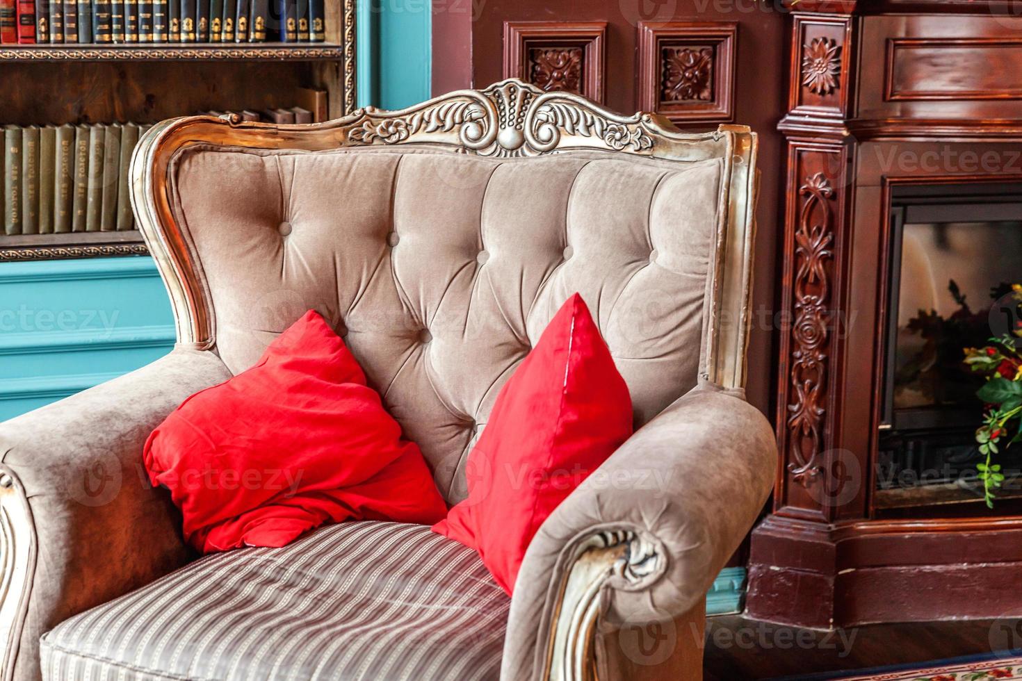 luxuriöses klassisches interieur der hausbibliothek. Wohnzimmer mit Bücherregal, Büchern, Sessel, Sofa und Kamin. saubere und moderne Dekoration mit eleganten Möbeln. bildung lesen studienweisheitskonzept. foto