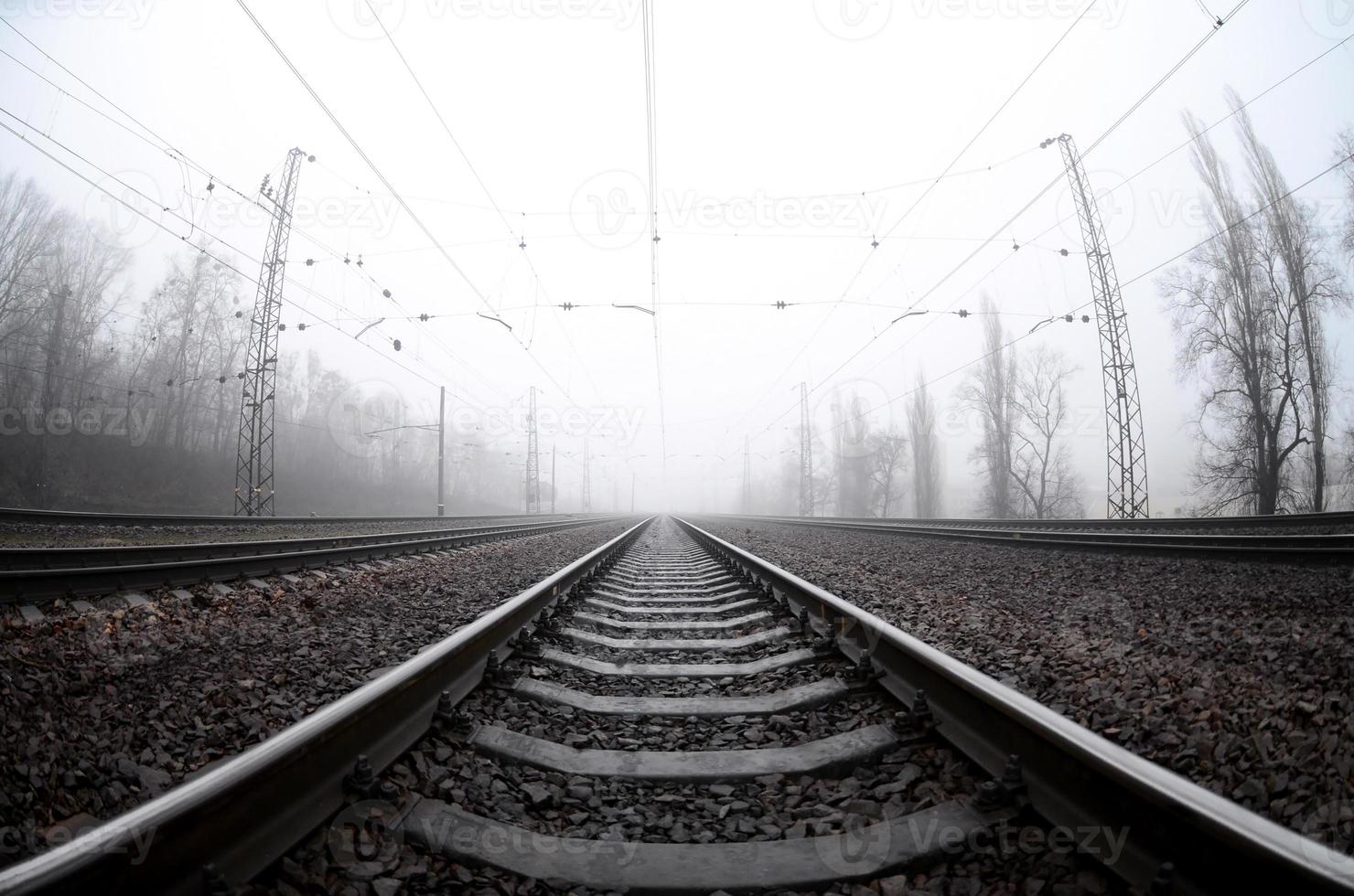 die Bahngleise an einem nebligen Morgen. viele schienen und schwellen gehen in den nebligen horizont. Fisheye-Foto mit erhöhter Verzerrung foto