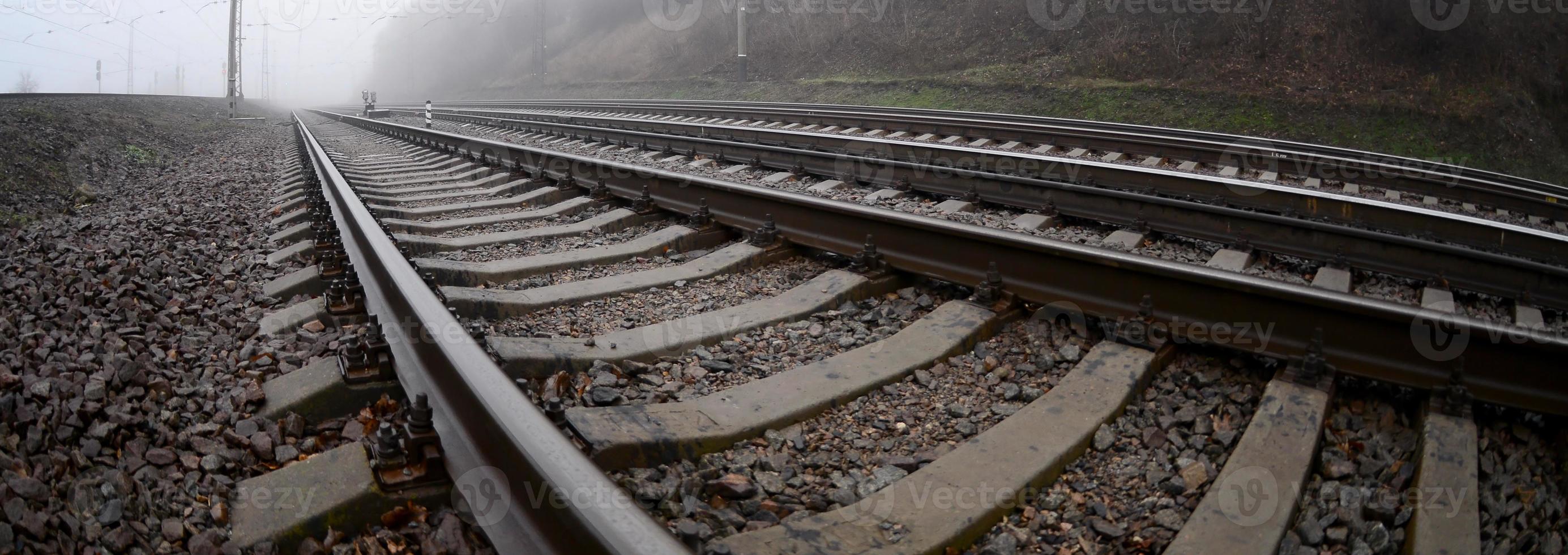 die Bahngleise an einem nebligen Morgen. viele schienen und schwellen gehen in den nebligen horizont. Fisheye-Foto mit erhöhter Verzerrung foto