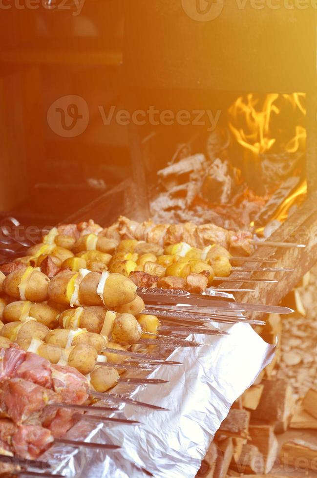 rohes Fleisch und Kartoffeln werden auf Metallspieße gepflanzt. der Prozess des Kochens von Schaschliks. Russisches und ukrainisches Lageressen foto